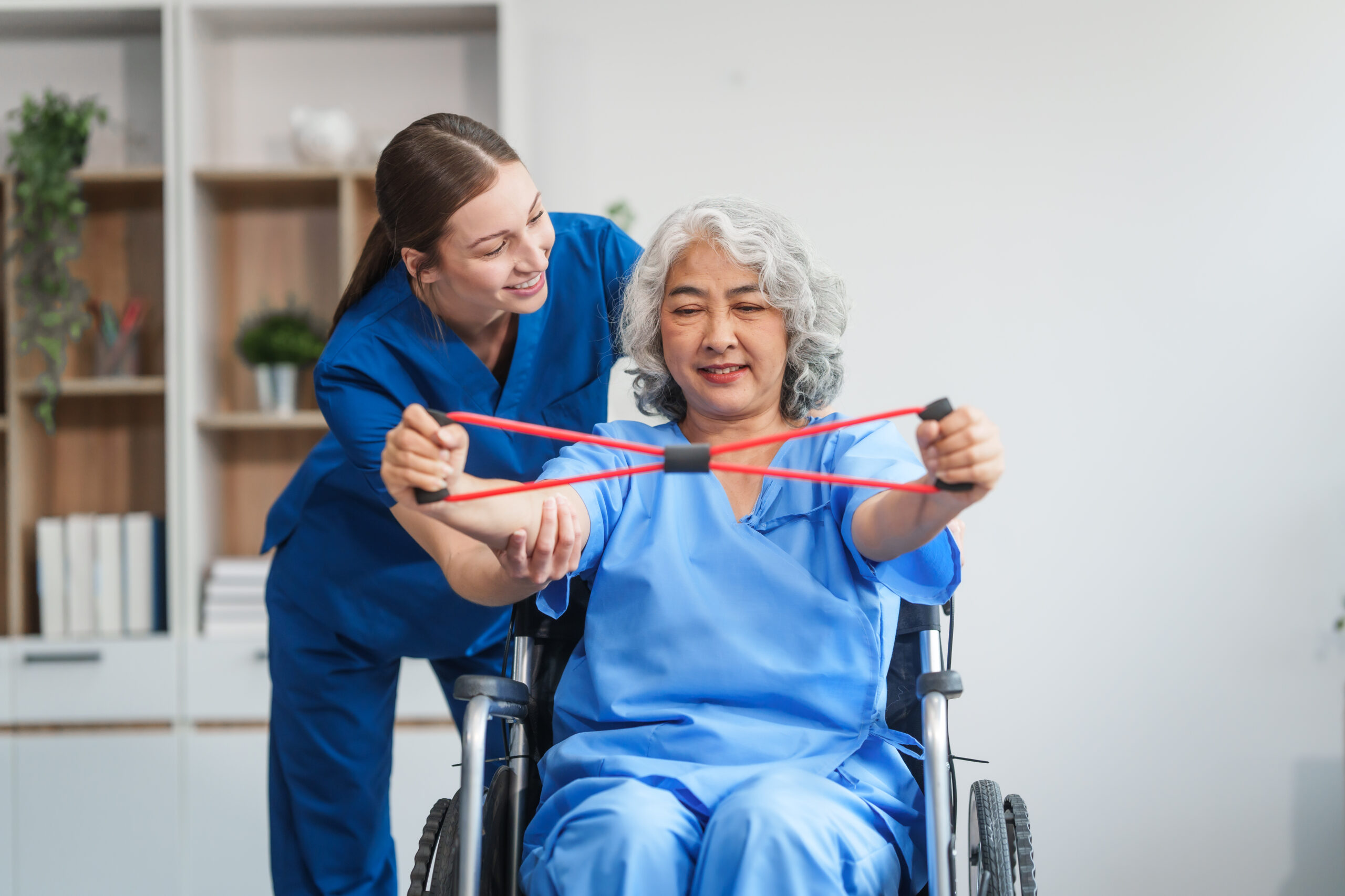 Senior woman in a wheelchair doing physical therapy exercises with the assistance of a smiling healthcare professional in a rehabilitation center. in home care services in philadelphia