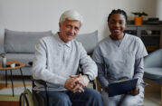 Smiling senior man in a wheelchair with a friendly home care nurse providing in-home healthcare support in a cozy living space. in home care services in philadelphia