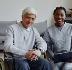 Smiling senior man in a wheelchair with a friendly home care nurse providing in-home healthcare support in a cozy living space. in home care services in philadelphia