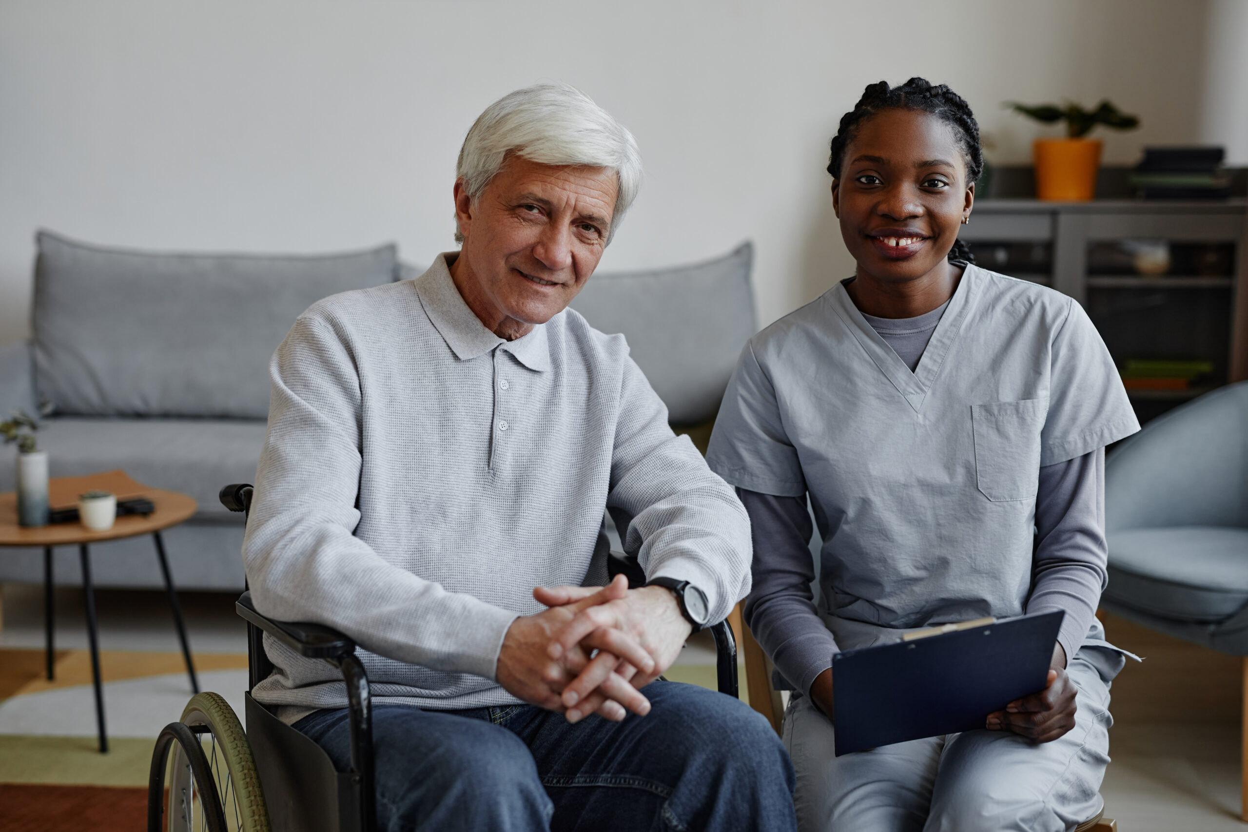 Smiling senior man in a wheelchair with a friendly home care nurse providing in-home healthcare support in a cozy living space. in home care services in philadelphia